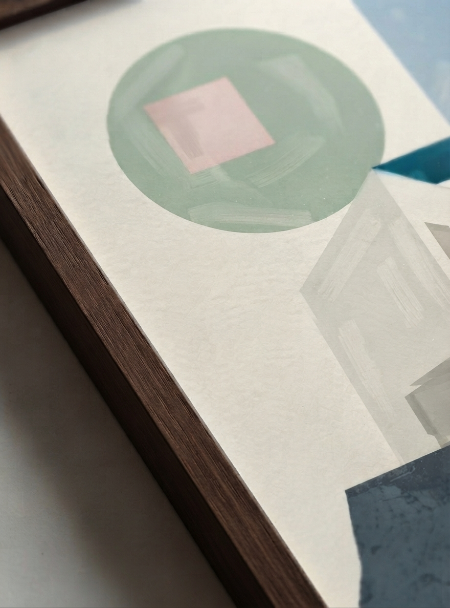 Close-up of a framed  Minimalist Abstract House Print featuring geometric architecture and timeless Mid-Century Modern style by artist Francis Phylae  featuring a sage green circle with a pink square, layered over light gray geometric shapes and a dark blue block, set in a dark wood frame.
