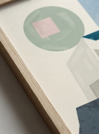 A close-up of a framed abstract Minimalist Abstract House Print featuring geometric architecture and timeless Mid-Century Modern style by artist Francis Phylae, featuring a sage green circle with a pink square inside, on a textured off-white background with a light wood frame.