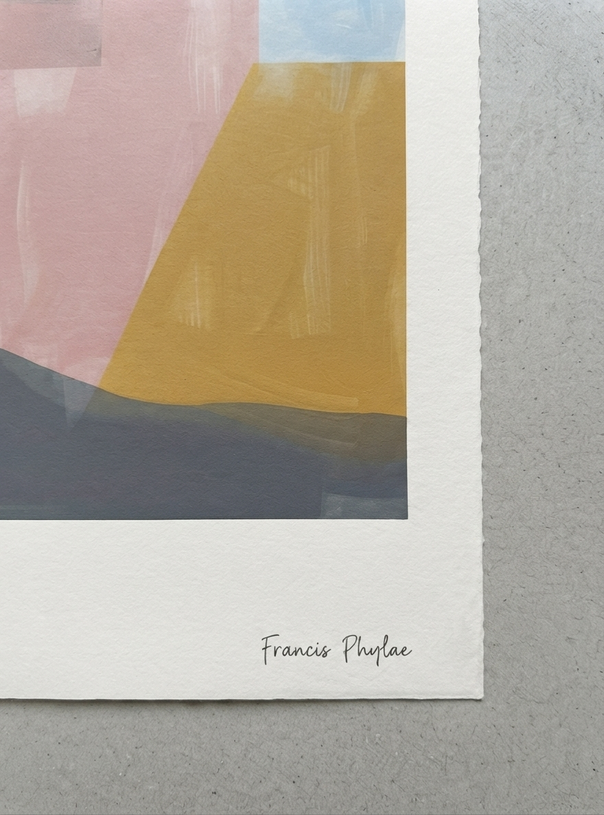 An Mid-Century Modern Geometric Landscape Art Print showcasing a multi-colour abstract landscape inspired by Mid Century Modern design from Francis Phylae at Phylae Posters featuring geometric shapes in pink, mustard yellow, light blue, and dark gray, with a wide white border and the name 'Francis Phylae' printed at the bottom, shown on a textured gray surface.